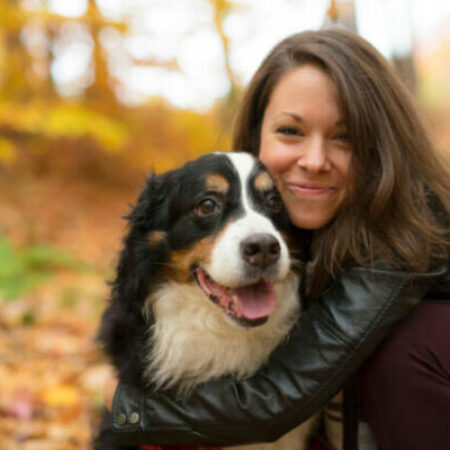 Junge Frau umarmt ihren Hund im herbstlichen Wald – liebevoller Start ins Leben mit dem ersten Hund